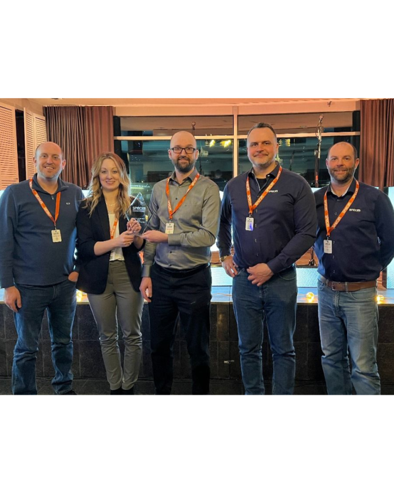 Channel systems and specim employees standing together holding distributor of the year trophy